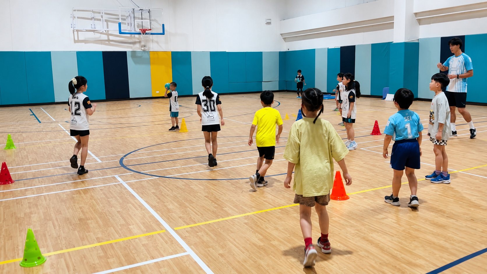 体育館で広がってウォームアップする子どもたちとコーチ