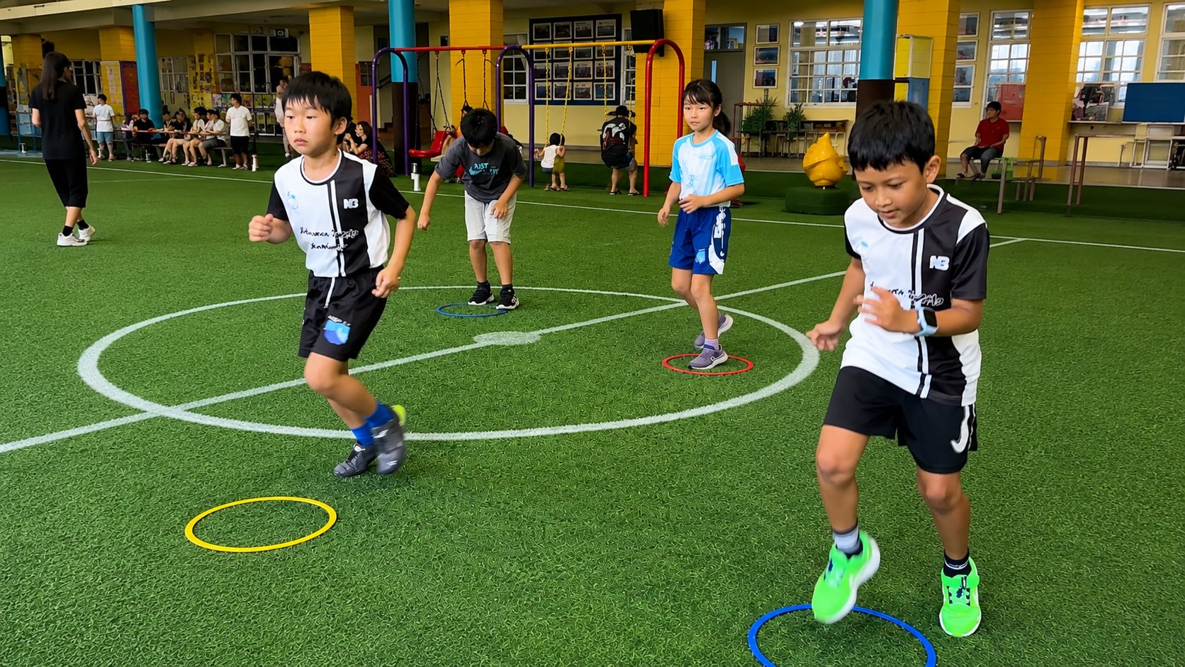 グラウンドでリングを使ったステップ練習に取り組む子ども