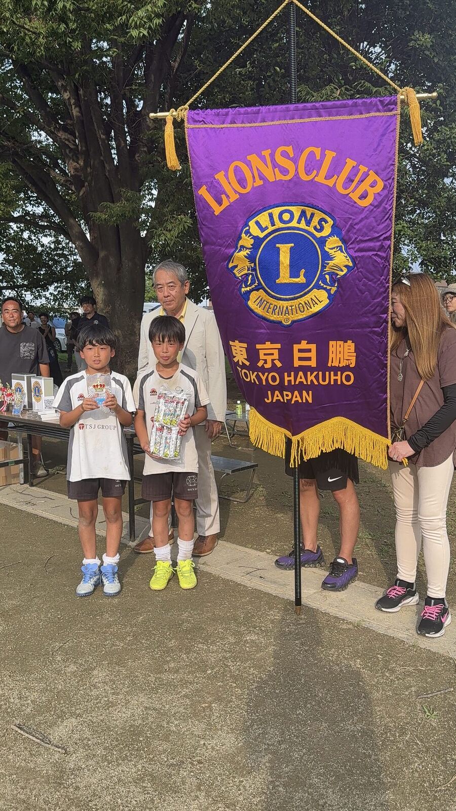 トロフィーと記念品を手にする選手と大会関係者