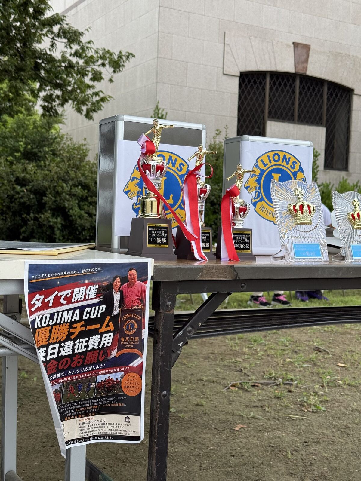 チャリティーCUPのトロフィーの隣に置かれたKOJIMA CUP募金フライヤー