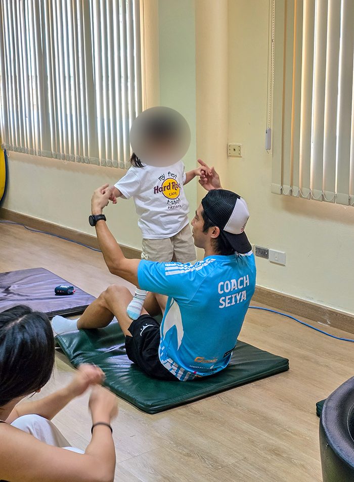 コーチと一緒に立つ練習をする子ども